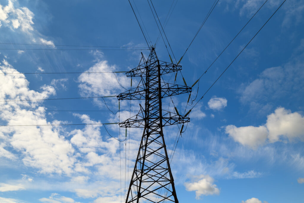 Ett elledningstorn mot en blå himmel och vita små moln