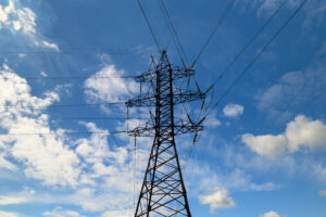 Ett elledningstorn mot en blå himmel och vita små moln