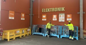 Två varselklädd personal står framför Elektronik på Vallentuna Returpark och visar den nya uppdelningen