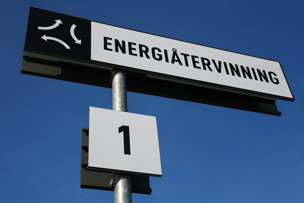 En skylt med texten Energiåtervinning och ett pictogram på svart bakgrundsfärg.